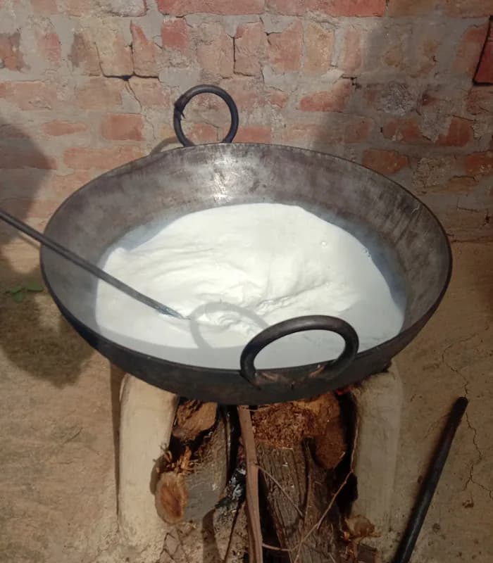 Milk reducing to khoya in an iron karahi over a wood-fired chulha