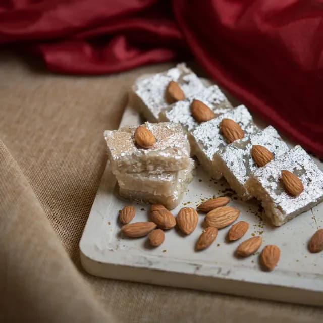 Badam barfi with silver leaf, each piece topped with an almond