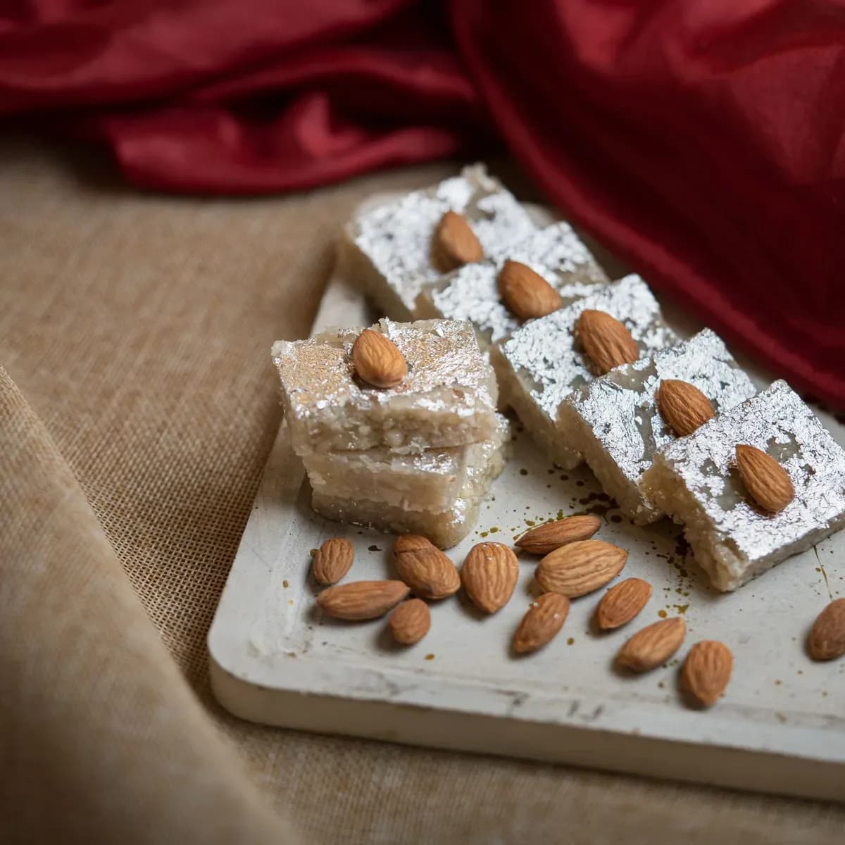 Badam barfi with silver leaf, each piece topped with an almond