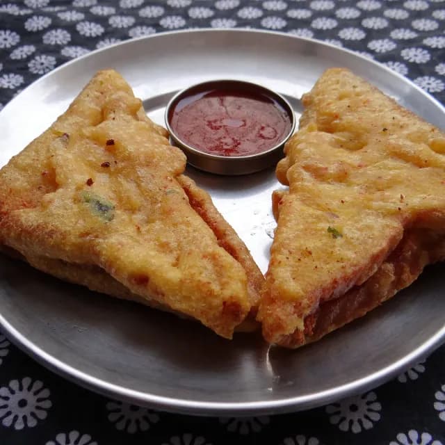Golden bread pakoras stuffed with spiced potato, with red chutney