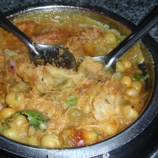 Samosa topped with spiced chhole, onion and sev