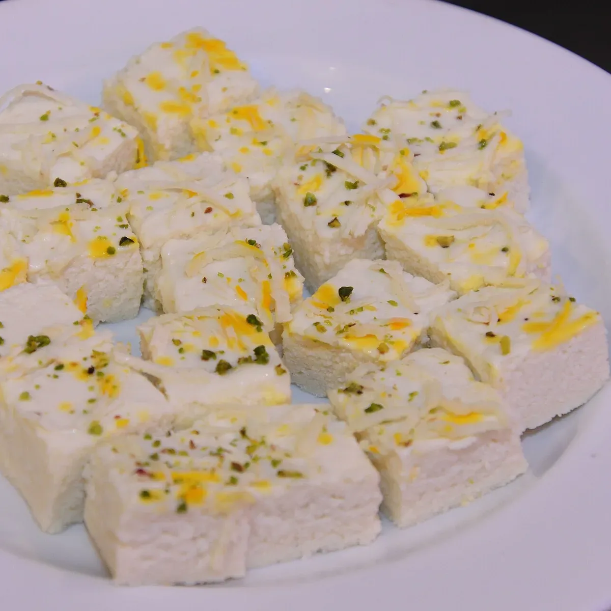 Soft white kalakand squares topped with pistachio and saffron