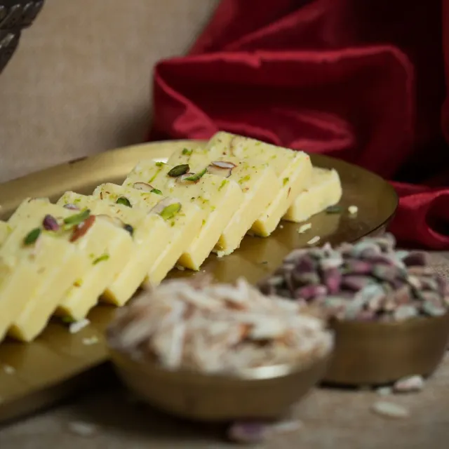 Slices of creamy milk barfi topped with pistachio