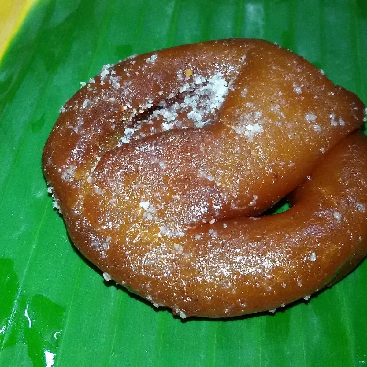 A glossy, dark paneer jalebi on a banana leaf